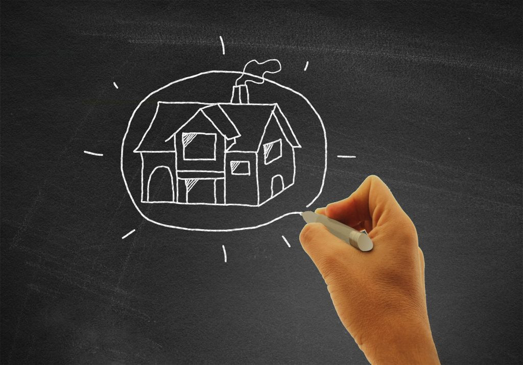 Hand drawing a house on blackboard - Real estate and housing con